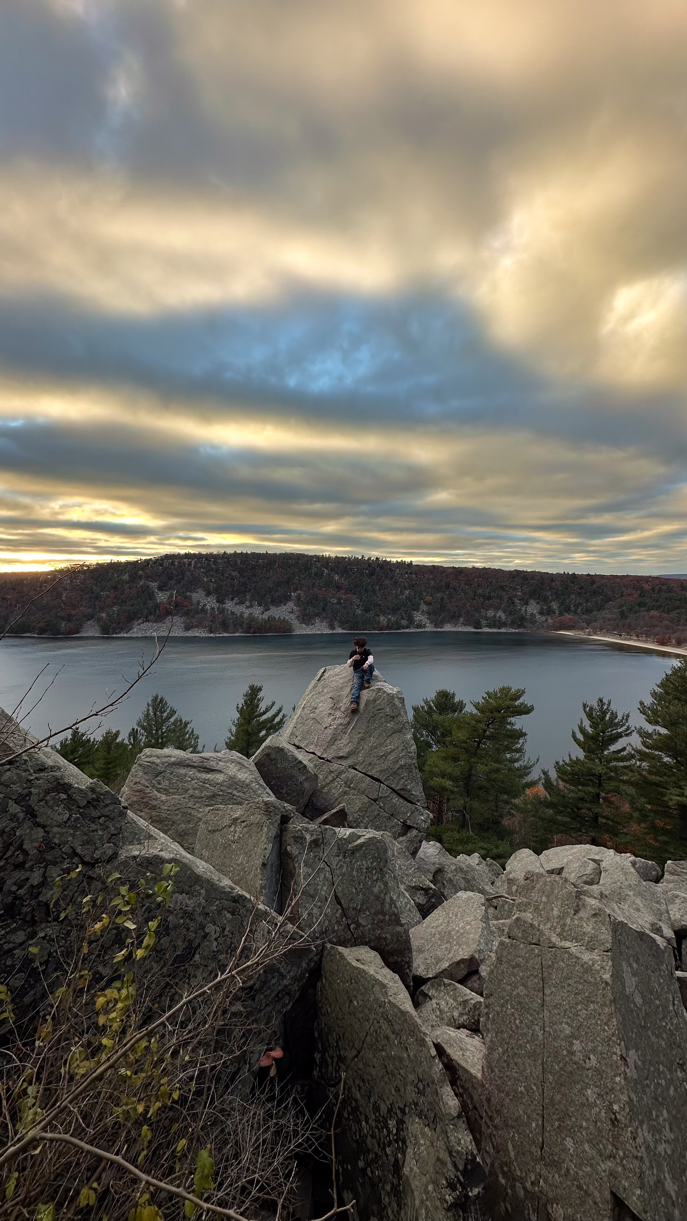 Person sitting on rocks high above Devils Lake at sunset
